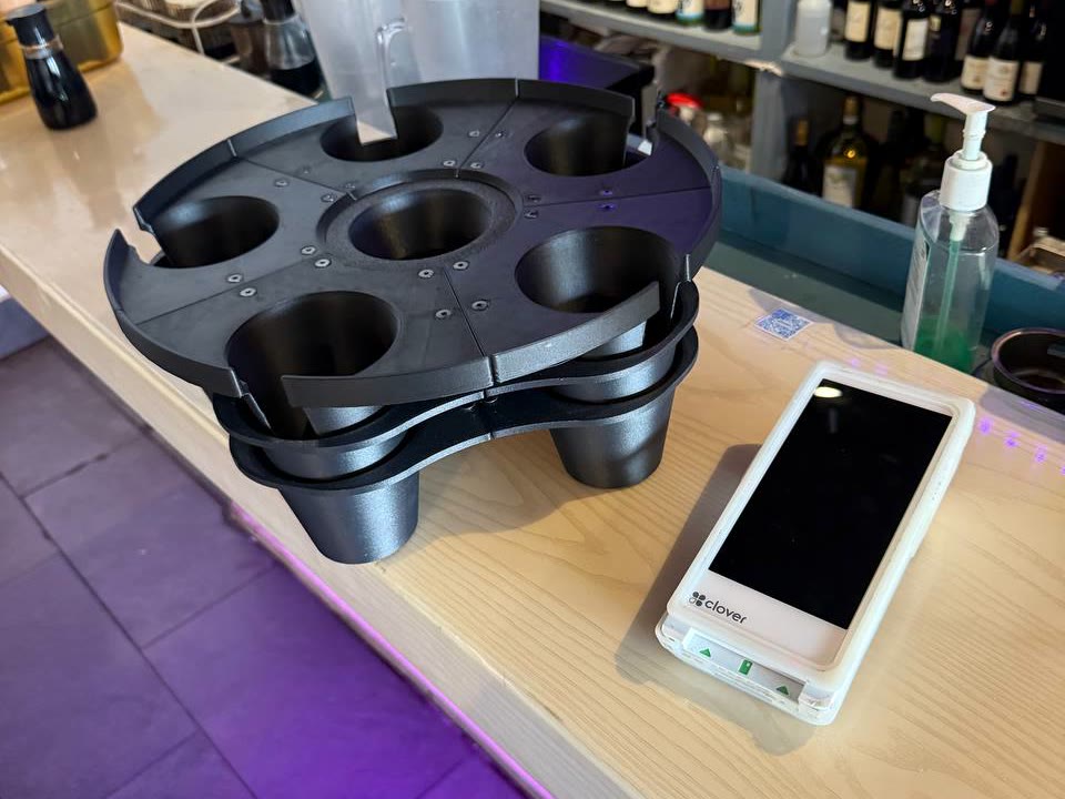 The GrippyTray on the same bar counter, its wells ready to lock every drink in place